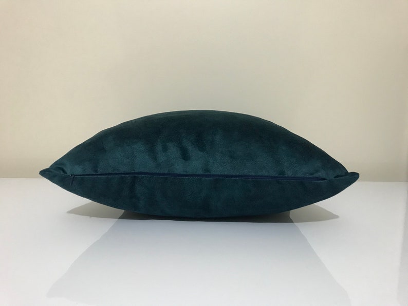 Op de afbeelding: Een teal fluwelen kussen met een rechthoekige vorm. Het kussen heeft een zachte, pluche textuur en een donker teal kleur. Het kussen is ontworpen voor woondecoratie en voegt een vleugje elegantie toe aan elke ruimte.