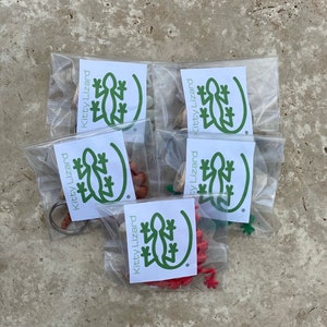 May include: Five clear plastic bags with green and white labels that say "Kitty Lizard" and contain small green, red, and brown lizard figurines.