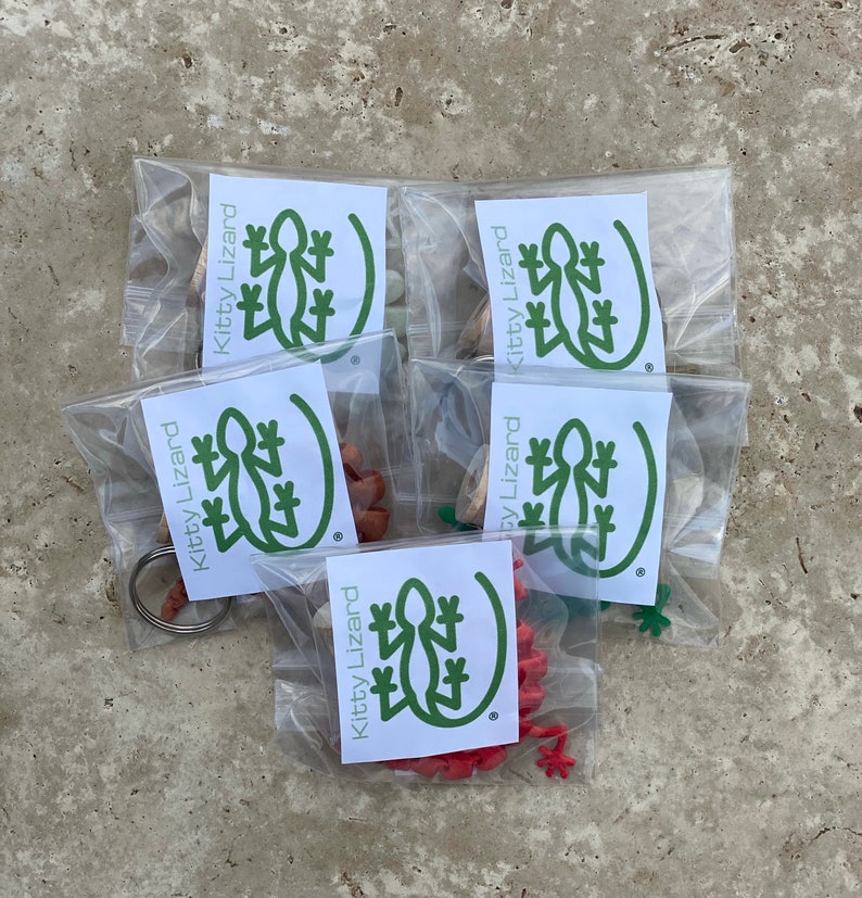 May include: Five clear plastic bags with green and white labels that say "Kitty Lizard" and contain small green, red, and brown lizard figurines.