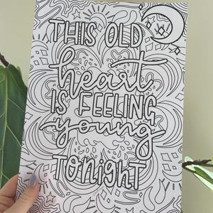 May include: Black and white art print with the words "THIS OLD HEART IS FEELING YOUNG TONIGHT" in a whimsical font. The design includes stars, moons, and swirling patterns, perfect for coloring or display.