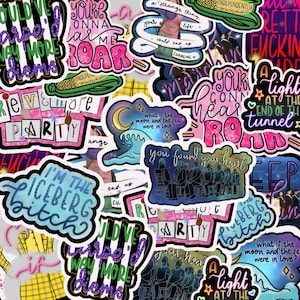 May include: A collection of colorful stickers with various designs and text. Some stickers feature phrases like "I'm the Iceberg Bitch," "You're Gonna Roar," and "What if the moon and the sea were in love?" The stickers have a mix of fonts and styles.