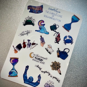 May include: A sheet of stickers with illustrations and text from "The Curious Case of Benjamin Button." Designs include an hourglass, musical notes, a crab, a teapot, and the phrases "live a little life" and "I think anything is possible."