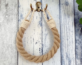 May include: A brown and cream rope towel ring hanging on a hook. The rope is twisted and has a natural texture.