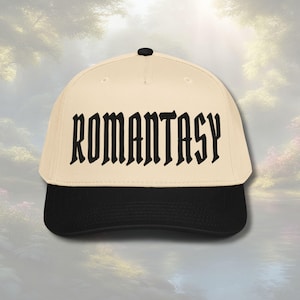 May include: A cream-colored baseball cap with a black brim and a black button on top. The word "ROMANTASY" is printed across the front in bold, gothic-style lettering.