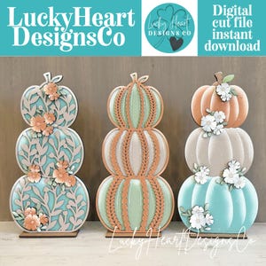 Peut inclure: Trois décorations de citrouilles empilées par LuckyHeartDesignsCo. La gauche présente des découpes florales bleu sarcelle et pêche. Le centre a des textures tressées menthe et cuivre. La droite montre des citrouilles pêche, beige et bleu sarcelle.