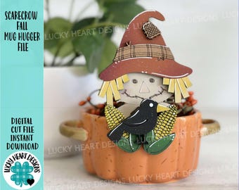 May include: A wooden scarecrow figurine with a black crow and corn stalks, sitting in a pumpkin-shaped mug holder. The scarecrow is wearing a brown hat with plaid accents and has a stitched face. The mug holder is orange with a textured surface.
