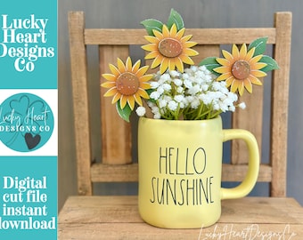 May include: A yellow ceramic mug with the black text HELLO SUNSHINE printed on the front. The mug contains three wooden sunflower cutouts with green leaves and a cluster of small white flowers. The mug has a single handle on the right side.
