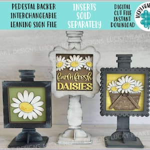 Może przedstawiać: Trzy dekoracyjne znaki na cokole z motywami stokrotek. Znaki są w czarno-białych ramkach, z napisem "Farm Fresh Daisies" na jednym. Znaki są wymienne i pochylone.