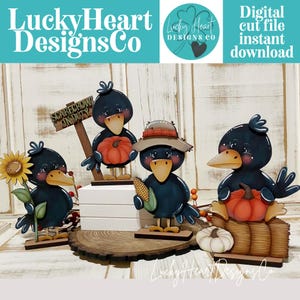 May include: A set of four decorative crow figures featuring autumn themes, including one holding a sunflower, one with a sign reading SCARECROW ON DUTY, one wearing a hat and holding corn, and one sitting on a hay bale with a pumpkin and white gourd.