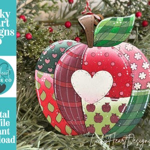 May include: A flat, apple-shaped ornament featuring a patchwork design with various patterns including red plaid, green plaid, small hearts, white flowers, and tiny red apples. A large, central white heart is stitched onto the front surface.