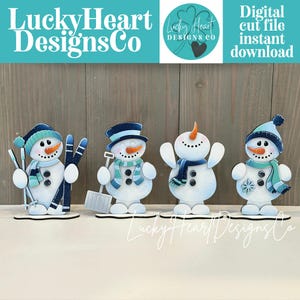May include: Four wooden snowman cutouts with winter accessories. Each snowman has a carrot nose, button eyes, and a scarf. One holds skis, another a shovel, and the others have outstretched arms. The text "LuckyHeart DesignsCo" is at the top.