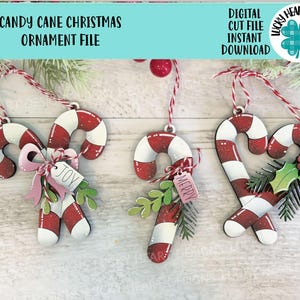 May include: Three candy cane Christmas ornaments with red and white stripes. One has a pink bow and a "JOY" tag, another has a "MERRY" tag, and the third has holly. The text "CANDY CANE CHRISTMAS ORNAMENT FILE" is at the top.