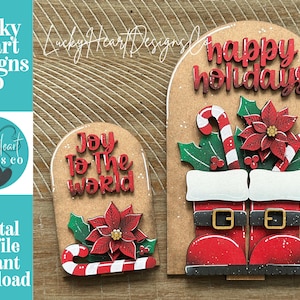 Könnte beinhalten: Zwei gewölbte Weihnachtsschilder aus Holz mit natürlichem Finish. Das kleinere Schild zeigt den Text Joy To The World, einen roten Weihnachtsstern und eine Zuckerstange. Das größere Schild zeigt den Text happy holidays, einen Weihnachtsstern und Stiefel.