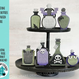May include: A set of seven Halloween potion bottles with various labels, including "Rat Tails", "Dragon Blood", "Arsenic Poison", and "Black Cat Hisses". The bottles are arranged on a two-tiered black stand.
