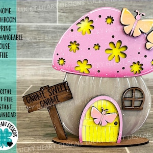May include: A pink and gray gnome mushroom house with a yellow door and a sign that reads "Gnome Sweet Gnome". The house has a pink mushroom cap with yellow flowers and white polka dots. There are two butterflies on the mushroom cap.