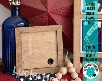 May include: A wooden leaning ladder frame with a single opening for a picture or photo. The frame is brown with a distressed finish. The frame is sitting on a red, white, and blue patterned surface.