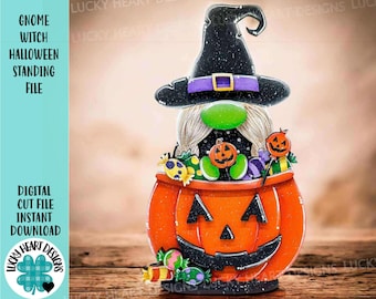 May include: A Halloween-themed gnome witch figurine. The gnome wears a black witch hat with a purple band and a green nose. It is inside an orange pumpkin with a carved face, filled with candies and jack-o'-lanterns. The text on the left says "Gnome Witch Halloween Standing File".
