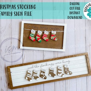 May include: A digital cut file for a Christmas stocking family sign. The sign features a white background with the text "and the stockings were hung" and a string of stockings with names on them. The sign is in a brown frame.