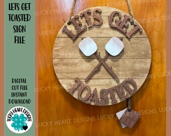 Könnte beinhalten: Ein Holzschild mit dem Text "Lets Get Toasted" in braunen Buchstaben. Das Schild ist mit zwei weißen Marshmallows auf Stöcken verziert, die sich kreuzen. Das Schild hängt an einer braunen Holzwand.