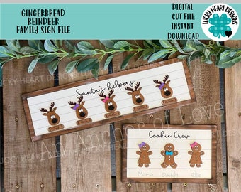 Può includere: Due cartelli in legno a tema natalizio. Il cartello superiore ha uno sfondo bianco con il testo "Santa's helpers" e tre renne di pan di zenzero con fiocchi rosa, viola e blu. Il cartello inferiore ha uno sfondo bianco con il testo "Cookie Crew" e tre personaggi di pan di zenzero con il testo "Mama", "Daddy" e "Ellie" sotto.