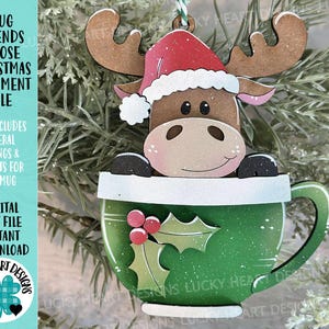 Peut inclure: Ornement de Noël en bois représentant un orignal portant un bonnet de Père Noël, sortant d'une tasse verte. La tasse est ornée de houx et de baies. Le texte sur l'ornement est "Mug Friends Moose Christmas Ornament File."