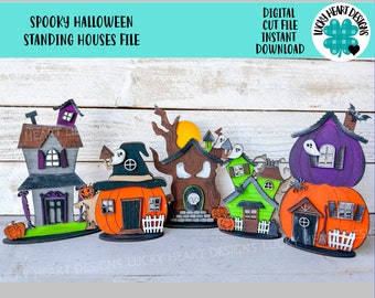 May include: A set of six spooky Halloween houses made of wood. The houses are painted in various colours, including purple, green, orange, and brown. Each house has a unique design, including a witch's hat, a ghost, and a skull. The houses are perfect for decorating for Halloween.