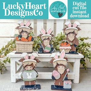 May include: A collection of wooden Highland cow figurines, each adorned with bunny ears and holding Easter-themed items like carrots and painted eggs. The figurines are displayed on a white bench, with the text "Lucky Heart Designs Co" visible.