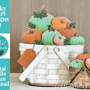 May include: A white basket overflowing with wooden pumpkins in shades of orange, green, and pink. A smaller basket with similar pumpkins sits in front. A tag reads "FARM FRESH PUMPKINS". The image also includes the text "Lucky Heart Designs Co" and "Digital cut file instant download".