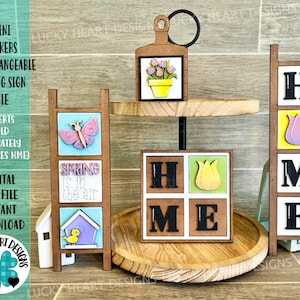 Peut inclure: Un plateau à étages en bois avec trois pancartes inclinées interchangeables. Les pancartes présentent un papillon, un motif sur le thème du printemps et le mot "HOME" avec des accents de tulipes. Les pancartes sont vendues séparément.