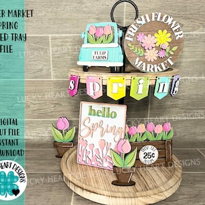 May include: A tiered tray decorated for spring with a wooden sign that says "hello spring" and a truck with the words "tulip farms" on it. The tray also has a sign that says "fresh flower market" and a banner that says "spring".