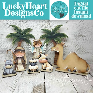 May include: A collection of wooden nativity scene figures, including a shepherd, angel, donkey, sheep, cow, and camel, with palm trees in the background. The figures are painted in soft colors and sit on individual bases. The text "Lucky Heart Designs Co" is visible.