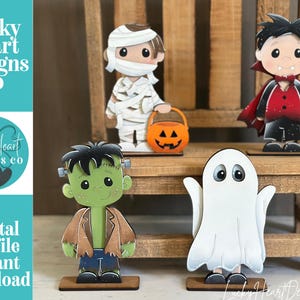 May include: Four Halloween-themed character cutouts including a mummy holding an orange pumpkin bucket, a vampire in a red and black cape, a green Frankenstein monster, and a white ghost. The text Lucky Heart Designs Co Digital cut file instant download is visible.