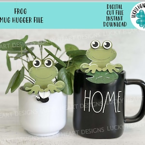 Puede incluir: Un archivo de corte digital de un abrazador de taza de rana verde claro, con el texto "FROG MUG HUGGER FILE" y "DIGITAL CUT FILE INSTANT DOWNLOAD". La rana está posada en una taza negra que dice "HOME".