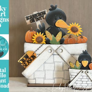 May include: A decorative wooden tiered tray set featuring two white woven-style baskets, black crows, orange pumpkins, yellow sunflowers, and corn cobs. One basket has a tag reading CROW SEASON and a sign reading SCARE CROW ON DUTY.