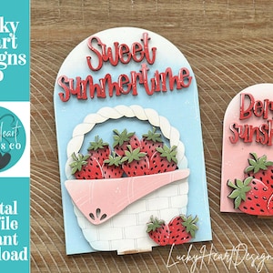 May include: Wooden strawberry-themed decorations. One features a basket of strawberries with "Sweet Summertime" text. The other has "Berry Sunshine" text and strawberries. The Lucky Heart Designs Co. logo is visible.