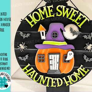 May include: A black and white round door hanger with the text "Home Sweet Haunted Home". A witch's hat sits atop a pumpkin house with a door and windows. Bats and spiders are scattered around the design.