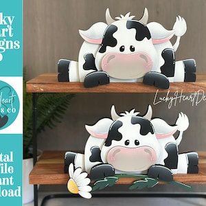 May include: Two wooden cow cutouts with black and white markings, sitting on a wooden shelf. The cows have pink noses and are decorated with a daisy and leaves. The text "Lucky Heart Designs Co" and "Digital cut file instant download" are visible.