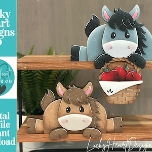May include: Wooden cutouts of a donkey and a horse, each with a friendly cartoon design. The donkey is gray with a basket of red apples. The horse is brown. The text "Lucky Heart Designs Co" and "Digital cut file instant download" are visible.