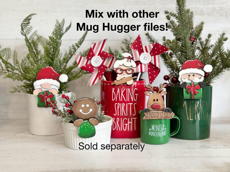May include: A set of five Christmas-themed mug huggers, including a gingerbread man, a reindeer, a Santa Claus, a woman with a rolling pin, and a snowman. The mug huggers are made of wood and painted in festive colors. The text "Baking Spirits Bright" is printed on a red mug. The text "Winter Wonderland" is printed on a green mug. The text "Reindeer Stables" is printed on a green mug. The text "Merry" is printed on a green mug. The text "Sold separately" is printed below the mugs.