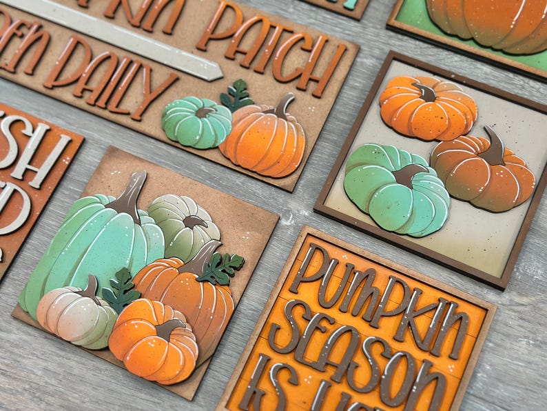 Peut inclure: Panneaux et carr&eacute;s d&eacute;coratifs en bois sur le th&egrave;me de l'automne, avec des citrouilles orange, vertes et cr&egrave;me. Certains panneaux portent des inscriptions telles que "Pumpkin Patch Daily" et "Pumpkin Season is Here". Les citrouilles sont en 3D avec des tiges et des feuilles d&eacute;taill&eacute;es.