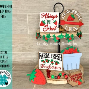 May include: A two-tiered wooden tray decorated with a strawberry theme. The top tier features a sign that says "Always Be Sweet" and a round sign that says "Strawberries U Pick". The bottom tier features a sign that says "Farm Fresh Strawberries", a small basket of strawberries, and a sign that says "Summer's my jam".