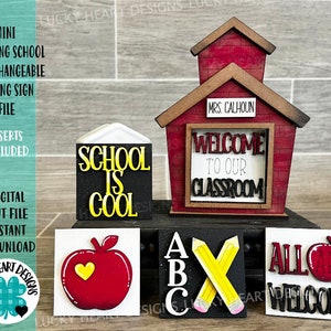 May include: A red wooden schoolhouse sign with interchangeable inserts. The sign features a welcome sign with the text "Welcome to our classroom". The inserts include "School is Cool", "ABC", "All are Welcome", and an apple with a heart.