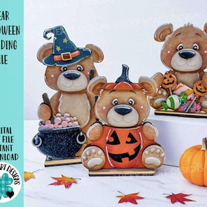 May include: Three wooden bear figurines with Halloween themes. One bear wears a witch hat and holds a cauldron, another is inside a jack-o'-lantern, and the third is surrounded by candy. The text "BEAR HALLOWEEN STANDING FILE" is visible.
