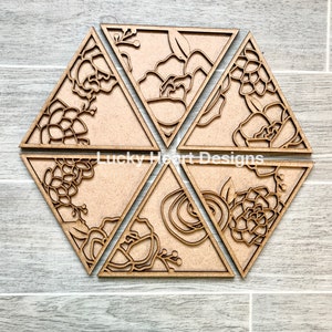 May include: Six wooden triangular coasters with intricate floral designs cut out. The coasters are arranged in a hexagonal pattern. The text "Lucky Heart Designs" is visible in the center.