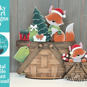 Könnte beinhalten: Weihnachtsdekoration aus Holz mit einem Fuchs mit Weihnachtsmütze und Schal, einem Weihnachtsbaum und Geschenken. Ein kleinerer Fuchs mit Zuckerstangen befindet sich in einem Korb. Der Text "Lucky Heart Designs Co" und "Digital cut file instant download" sind sichtbar.