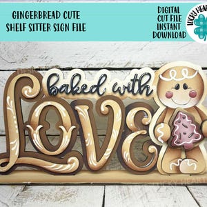 Puede incluir: Un letrero de madera para estante con las palabras "baked with love" en letras marrones y blancas. Un hombre de jengibre sostiene una galleta rosa en forma de árbol. El letrero también incluye el texto "Gingerbread Cute Shelf Sitter Sign File".