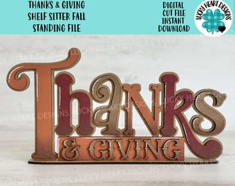 May include: A wooden shelf sitter sign with the words "Thanks & Giving" in a fall-themed color scheme. The sign is designed for a standing display and is perfect for fall decor.