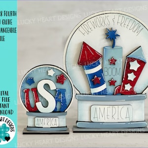 May include: Two wooden snow globes with interchangeable designs. The larger globe features a red, white, and blue firework design with the text "Fireworks & Freedom" and "America". The smaller globe features a red, white, and blue "USA" design with the text "America".