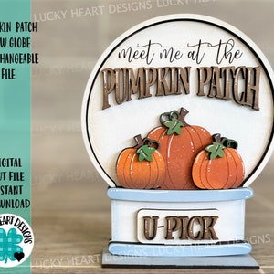 May include: A wooden pumpkin patch snow globe with the text "Meet me at the Pumpkin Patch" and "U-Pick". The snow globe is decorated with three orange pumpkins with green stems and leaves.