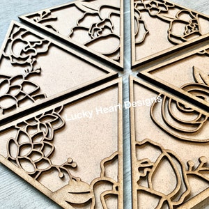 May include: Six wooden triangle-shaped signs with intricate floral designs cut out. The designs include flowers, leaves, and vines. The signs are unfinished and ready to be painted or stained.